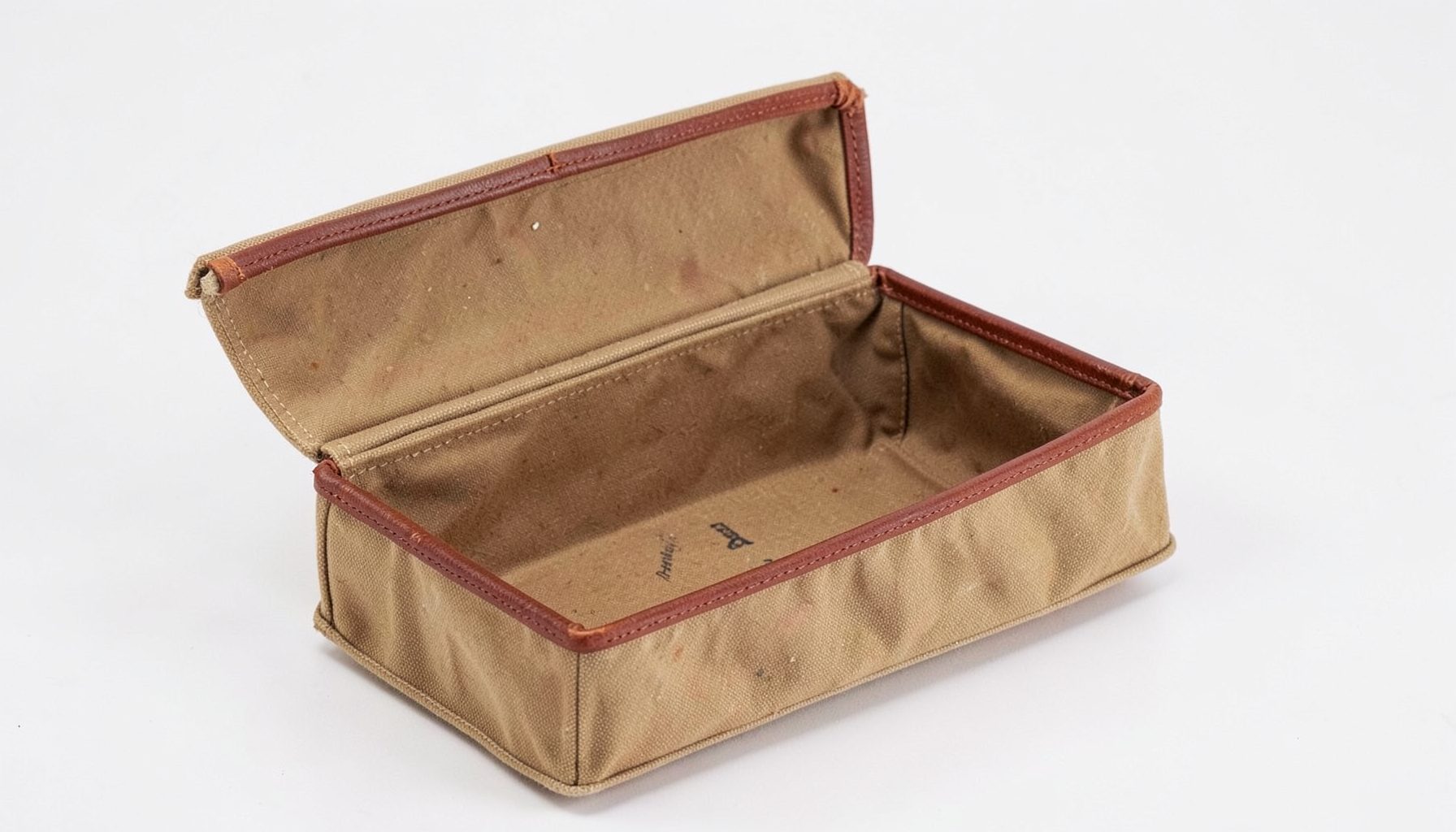 A classic waxed canvas dopp kit with Horween leather trim, open to reveal its spacious interior.