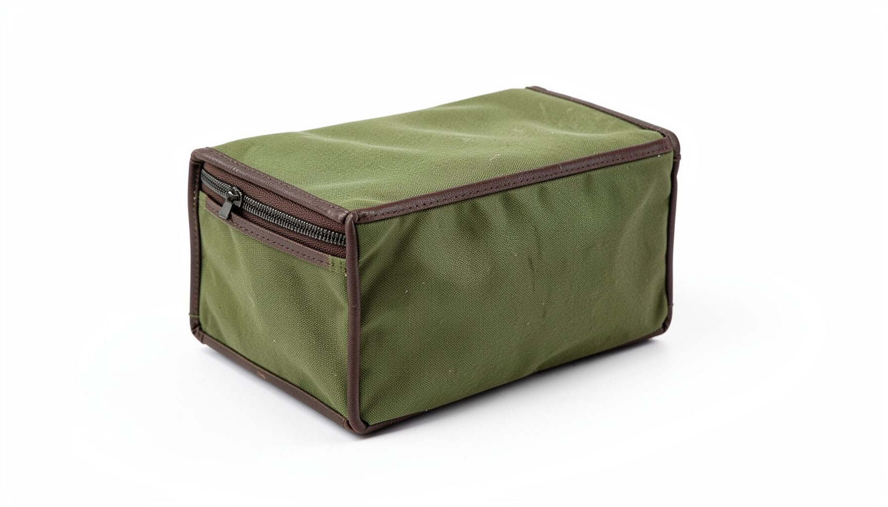 A compact standard waxed canvas dopp kit in olive green with dark brown leather trim, zipper closed, resting on a clean white background.
